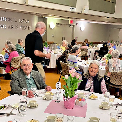 A cheerful gathering of elderly individuals enjoying a meal and conversation in a community dining hall.