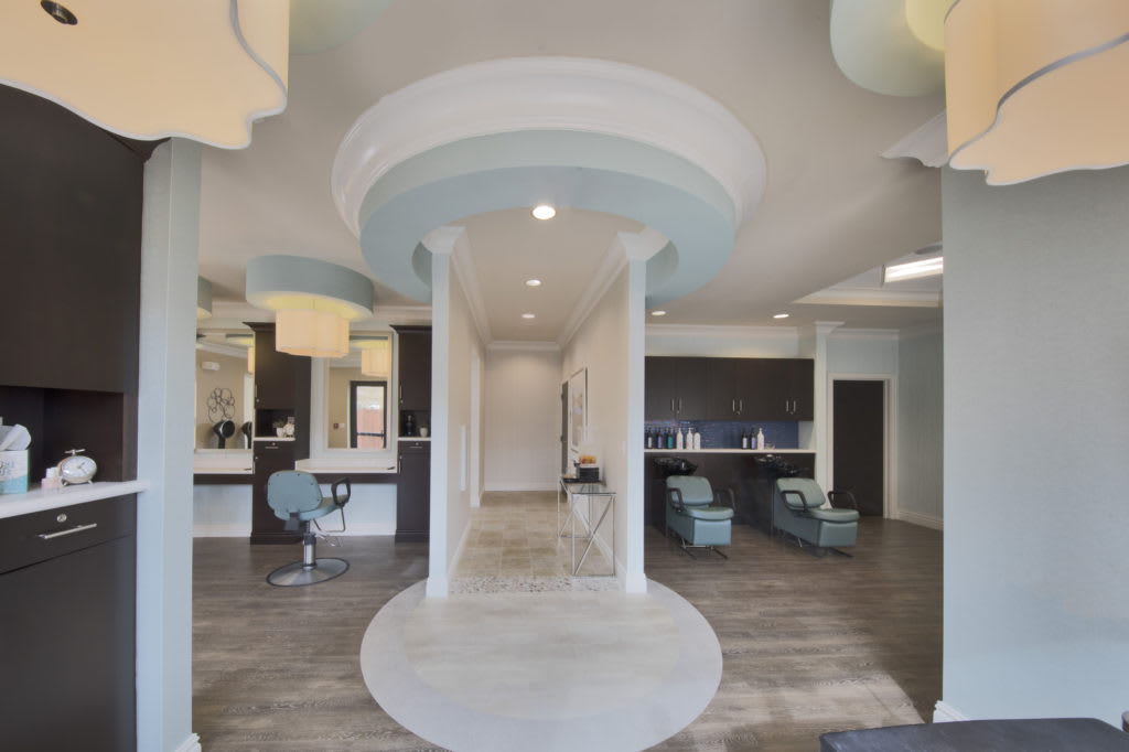 A modern hair salon interior with stylish decor, featuring columns, mirrors, and comfortable seating.