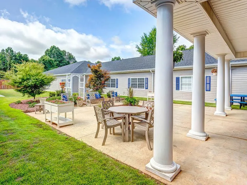 A beautiful patio with outdoor furniture and columns, set in a sunny garden.