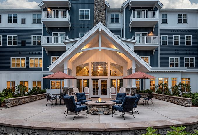 A well-lit building exterior with outdoor seating around a fire pit.