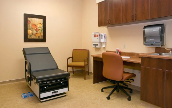 A clean and organized doctor's exam room with medical equipment and seating.