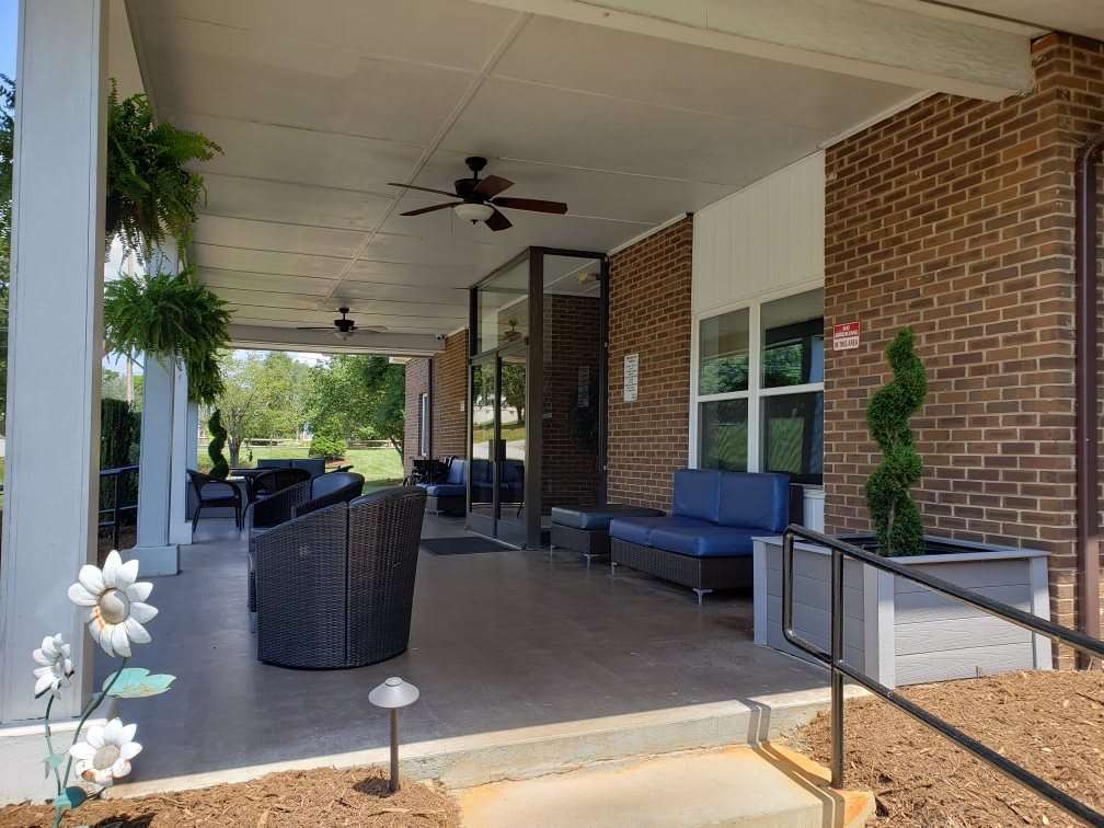 A cozy porch with comfortable outdoor seating and lush plants.
