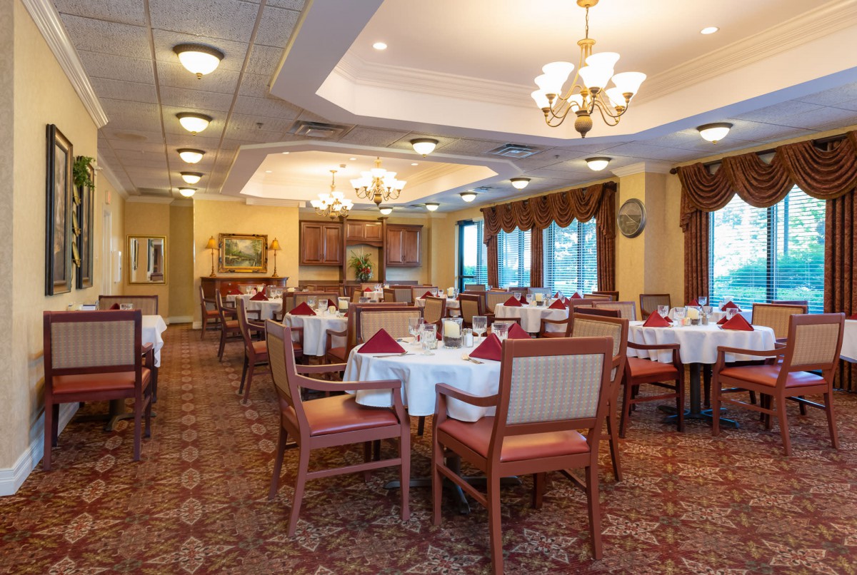 An elegant dining room with neatly arranged tables and chairs, adorned with chandeliers.
