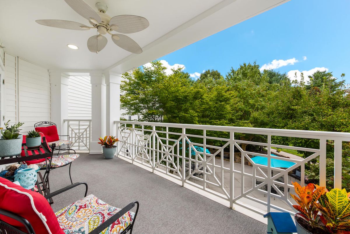 A cozy balcony with comfortable seating and a view of lush greenery.