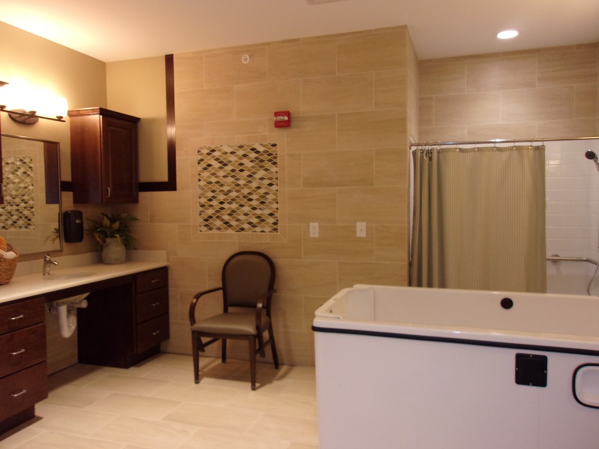 Modern bathroom with a bathtub, chair, and decorative wall art.