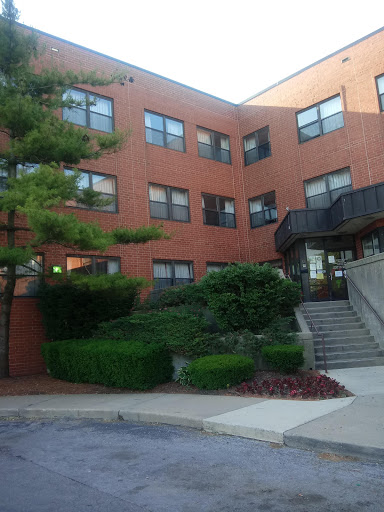 A brick apartment building featuring well-maintained landscaping and stair access.