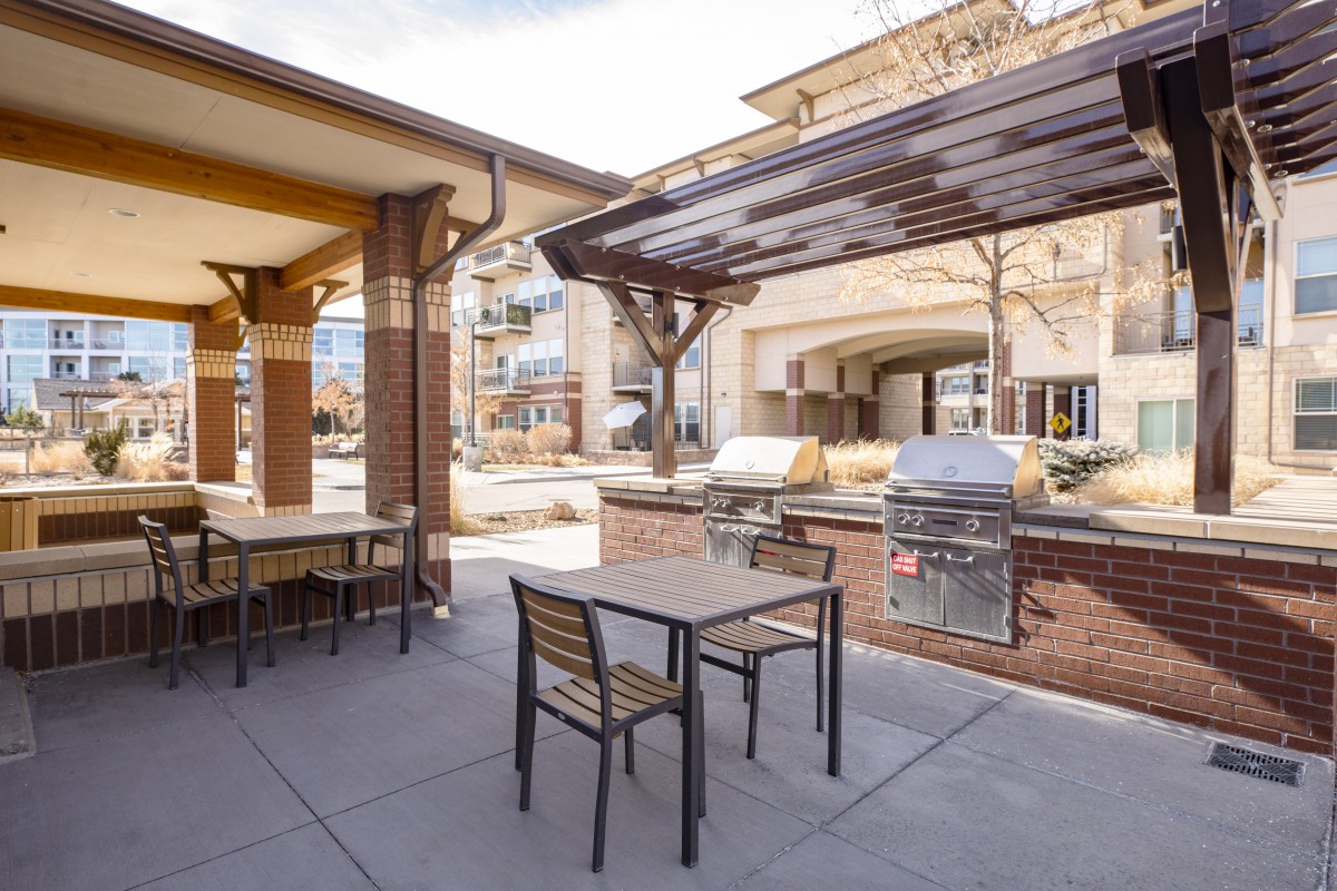 Outdoor patio area with BBQ grills and seating at an apartment complex.