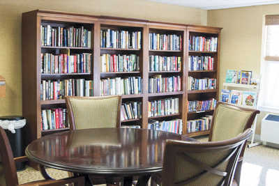 A cozy reading room with bookshelves and a round table surrounded by chairs.