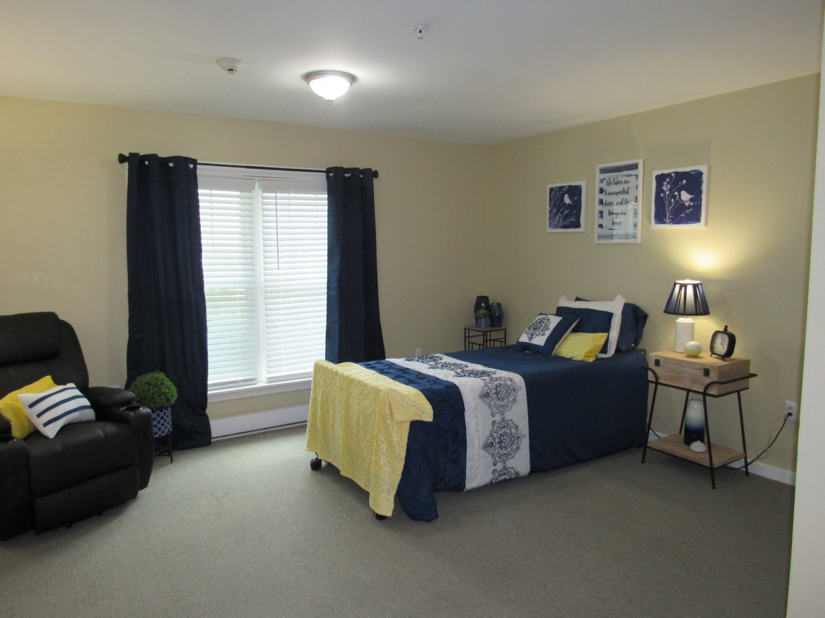 A cozy and well-decorated bedroom with a neatly made bed, dark curtains, and soft lighting.