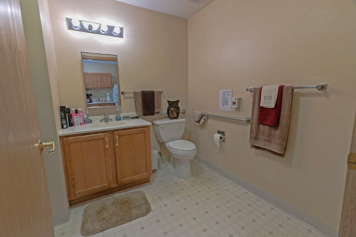 A well-organized bathroom with a sink, mirror, and toilet, featuring neutral-colored walls and accessories.