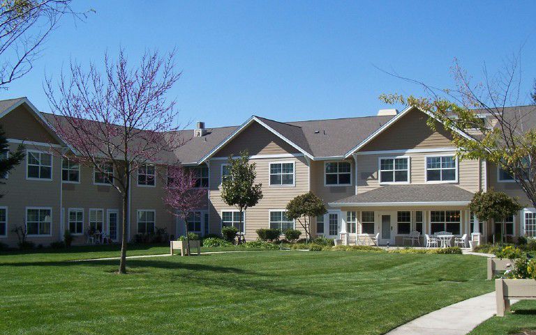 A two-story residential building with a well-maintained lawn and clear blue sky.