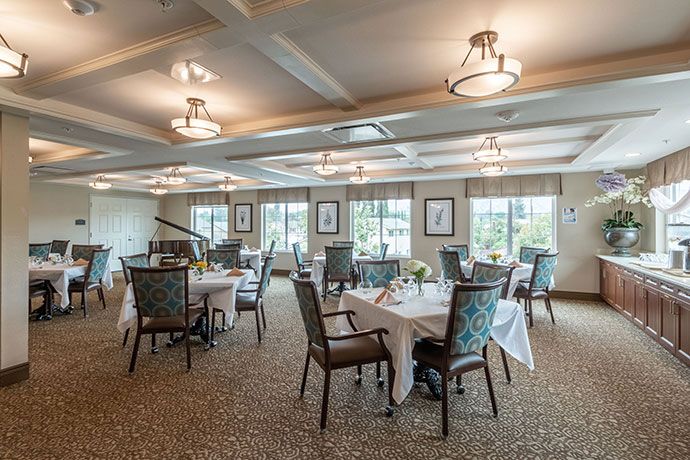 An elegantly decorated dining room with neatly arranged tables and chairs, illuminated by warm lighting.