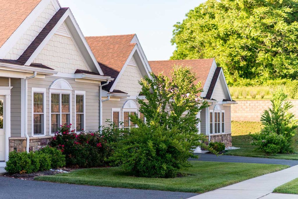 A row of suburban houses with well-maintained lawns and greenery.