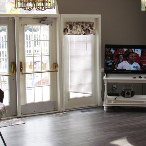 A cozy living room featuring a television, large windows, and stylish furniture.