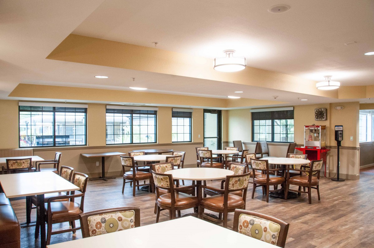 An empty dining room with neatly arranged chairs and tables, featuring large windows.