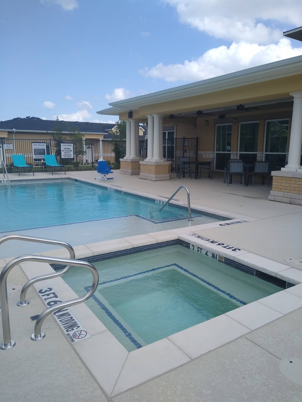 Outdoor swimming pool and hot tub area with adjacent patio seating.