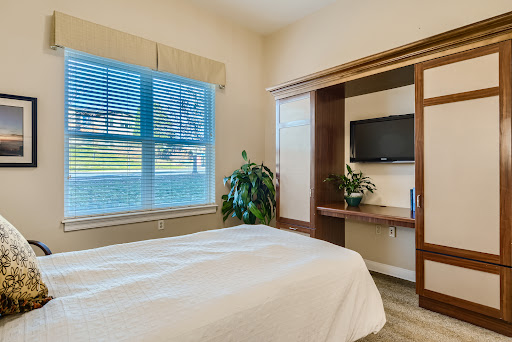 A cozy bedroom featuring a comfortable bed, natural light from a window, and stylish wooden furnishings.