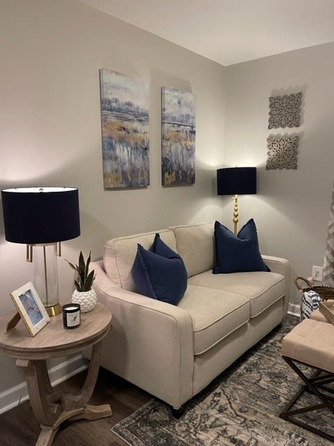 A cozy living room with a beige sofa, navy cushions, and artistic wall decor.