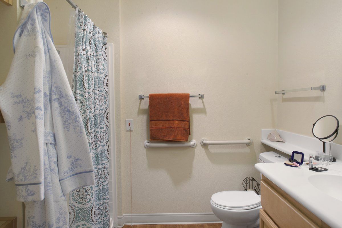 A bathroom with a shower curtain, orange towel, and basic amenities.