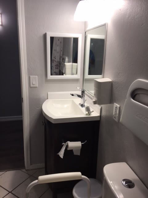 A modern bathroom with a sink, mirror, and toilet paper holder.