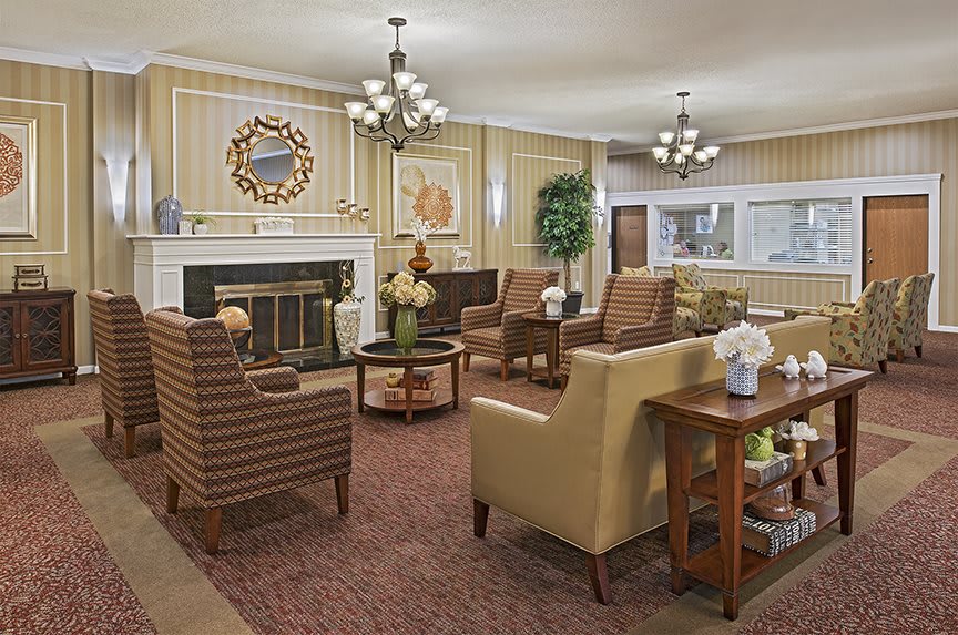 A cozy living room with comfortable seating, a fireplace, and elegant chandeliers.