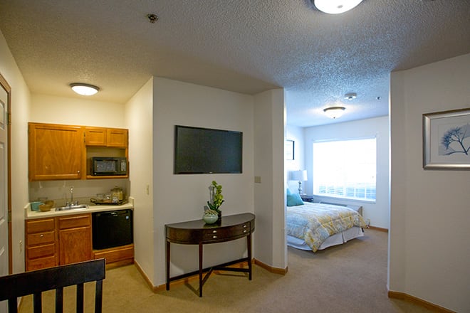 A modern studio apartment with a kitchenette and cozy bedroom area.