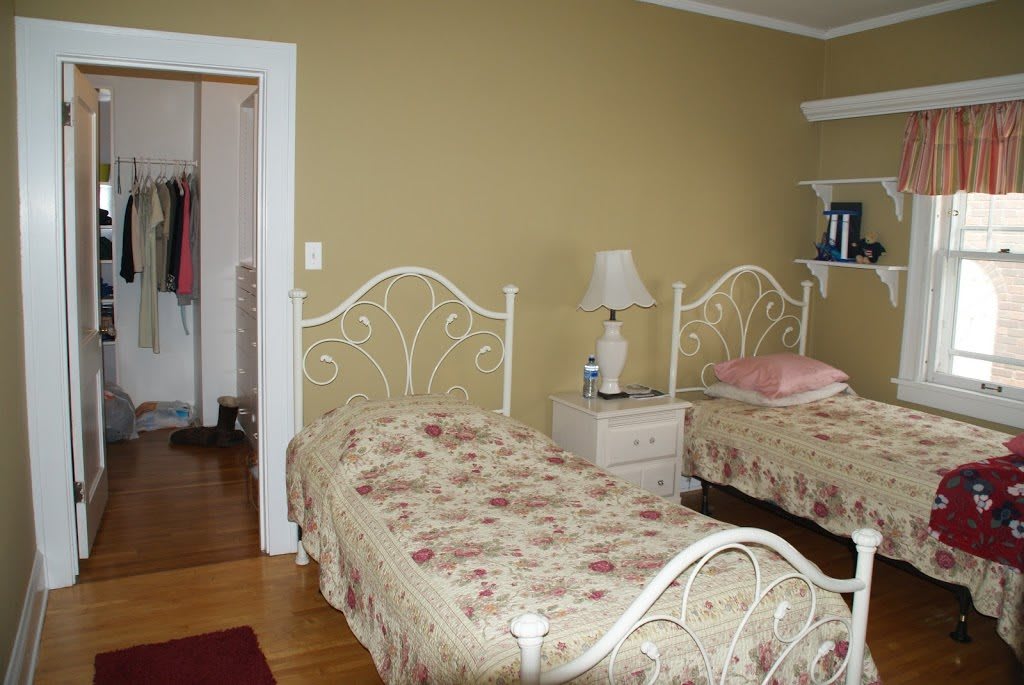 A cozy bedroom with twin beds adorned in floral bedspreads, featuring a nightstand and lamp.