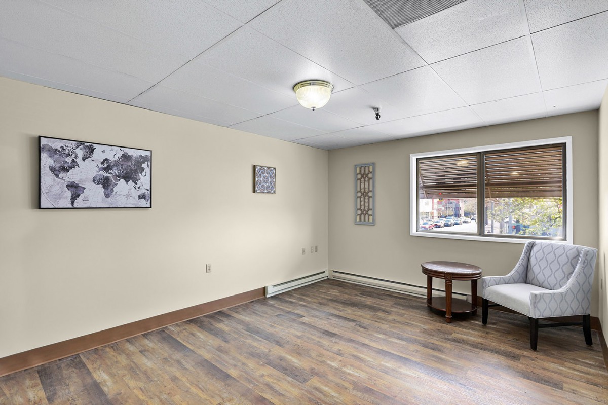 A simple living room interior with wooden flooring, a small table, and wall decor.