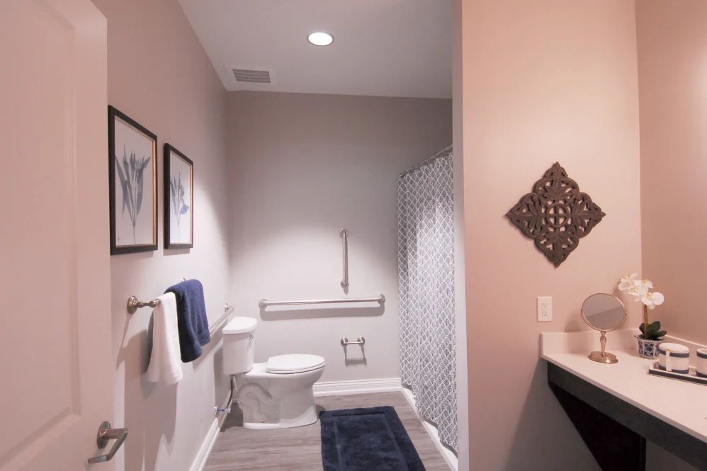 A modern bathroom featuring a toilet, shower with curtain, and tasteful decor including towels and wall art.