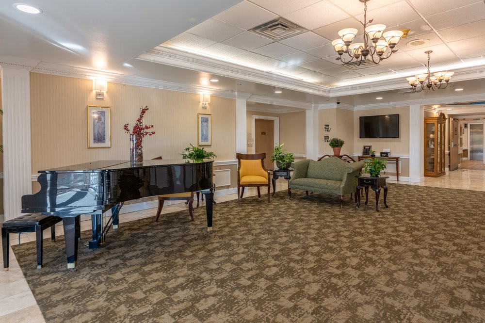 A well-decorated lobby with a grand piano, comfortable seating, and elegant lighting.