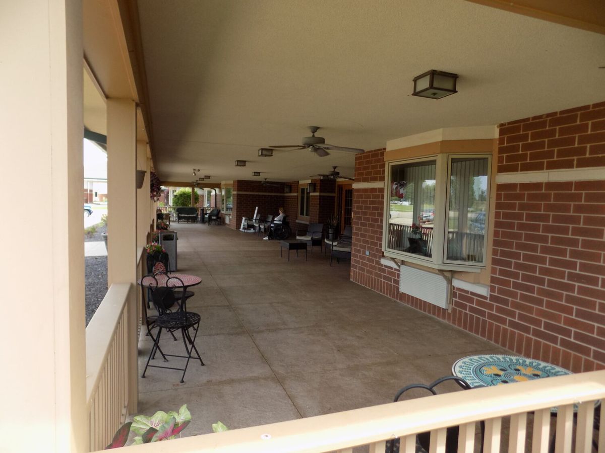 A spacious, covered outdoor patio with furniture and ceiling fans.