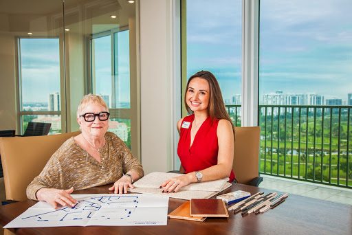 Two women engaged in a design meeting with plans and materials on the table, overlooking a scenic view.