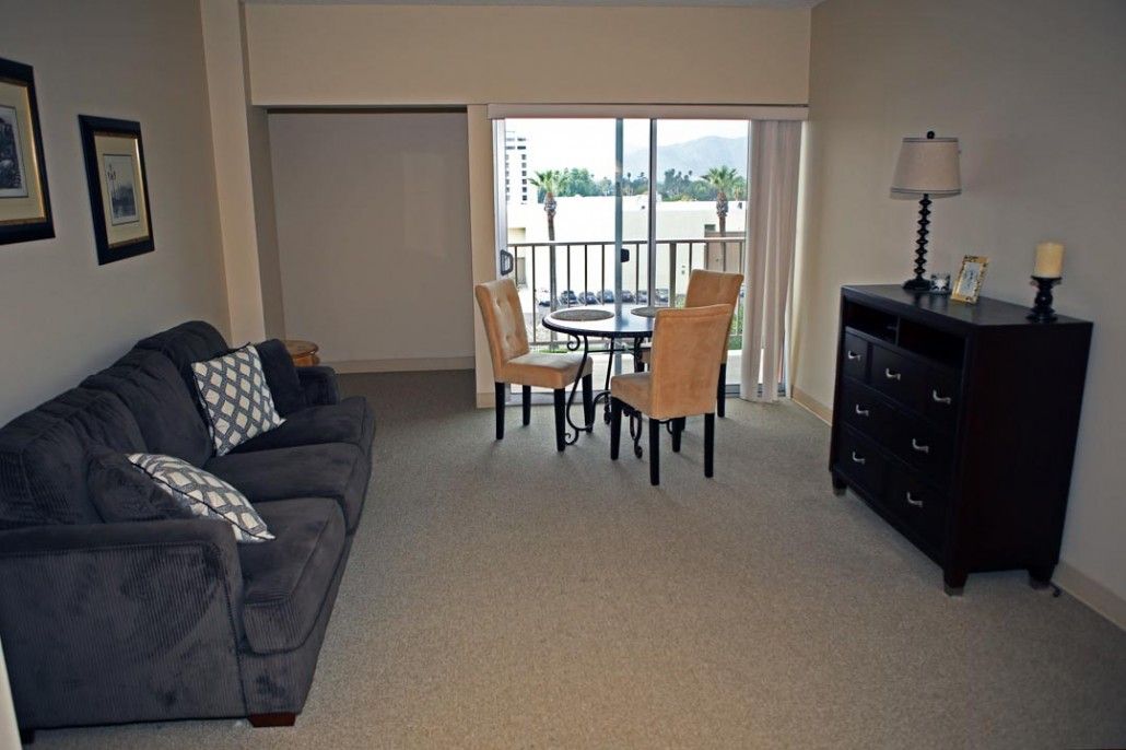 A cozy living room with a dining area, featuring a sofa, chairs, table, and access to a balcony.
