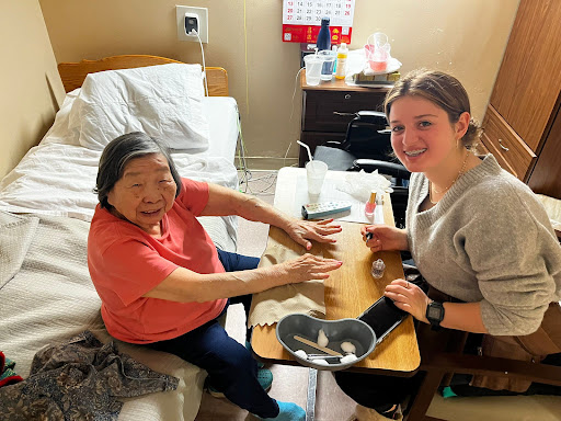 A caregiver and an elderly resident enjoy a creative moment together, showcasing the joy of companionship in a nursing home.