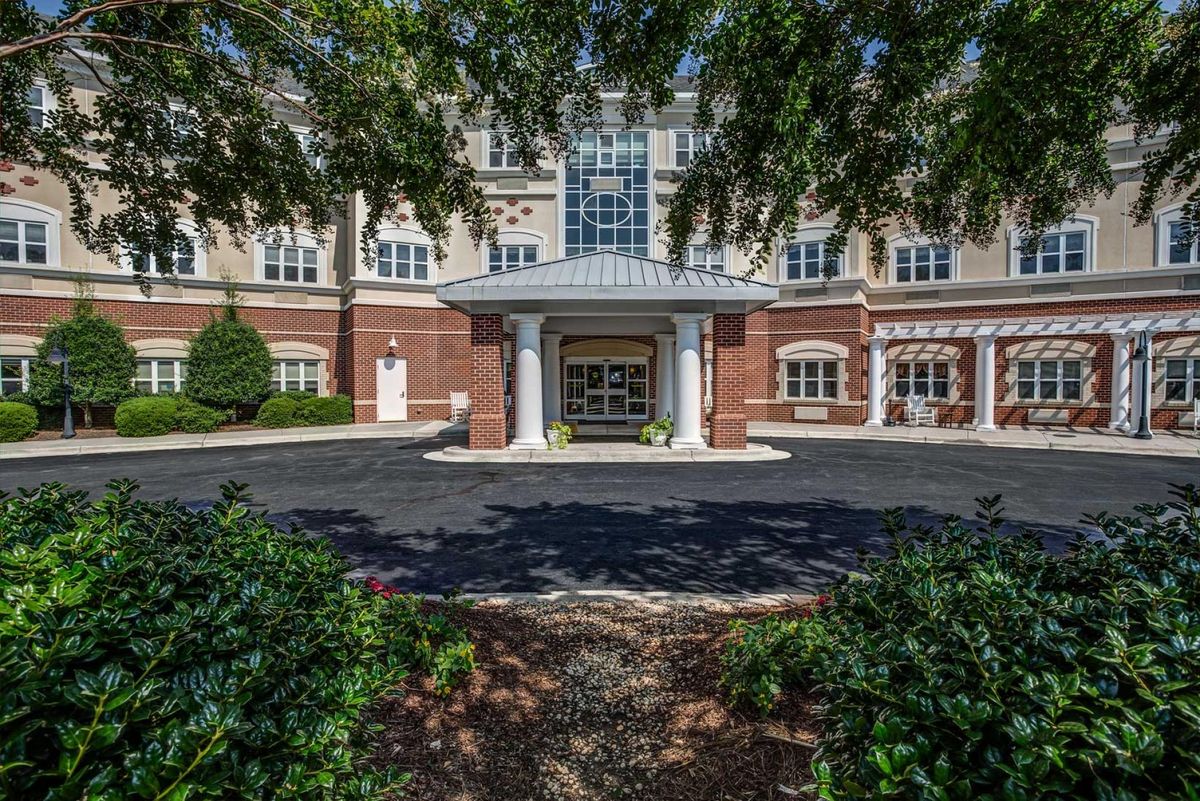 A welcoming entrance to a building framed by greenery and trees.
