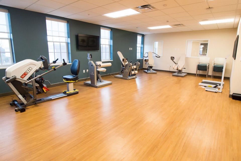 A well-lit gym with various exercise machines arranged along the walls.