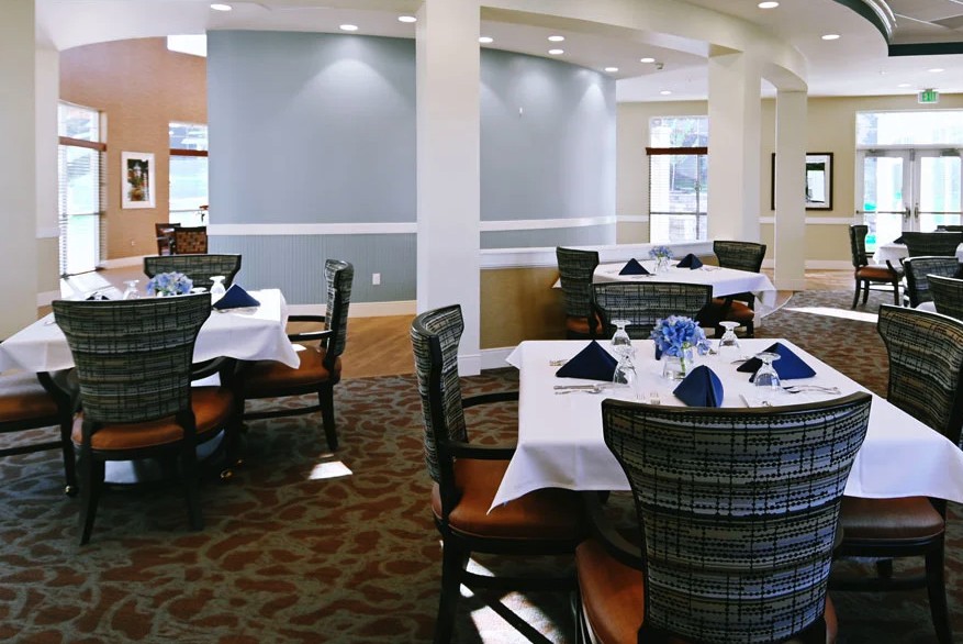 A neatly arranged dining area in a restaurant with blue napkins and elegantly set tables.