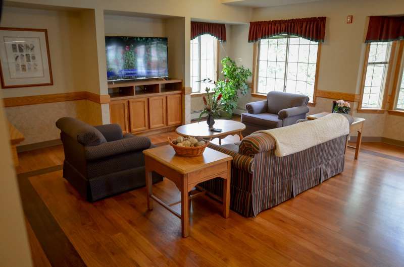 A cozy living room with a television, sofas, and a coffee table on a wooden floor.