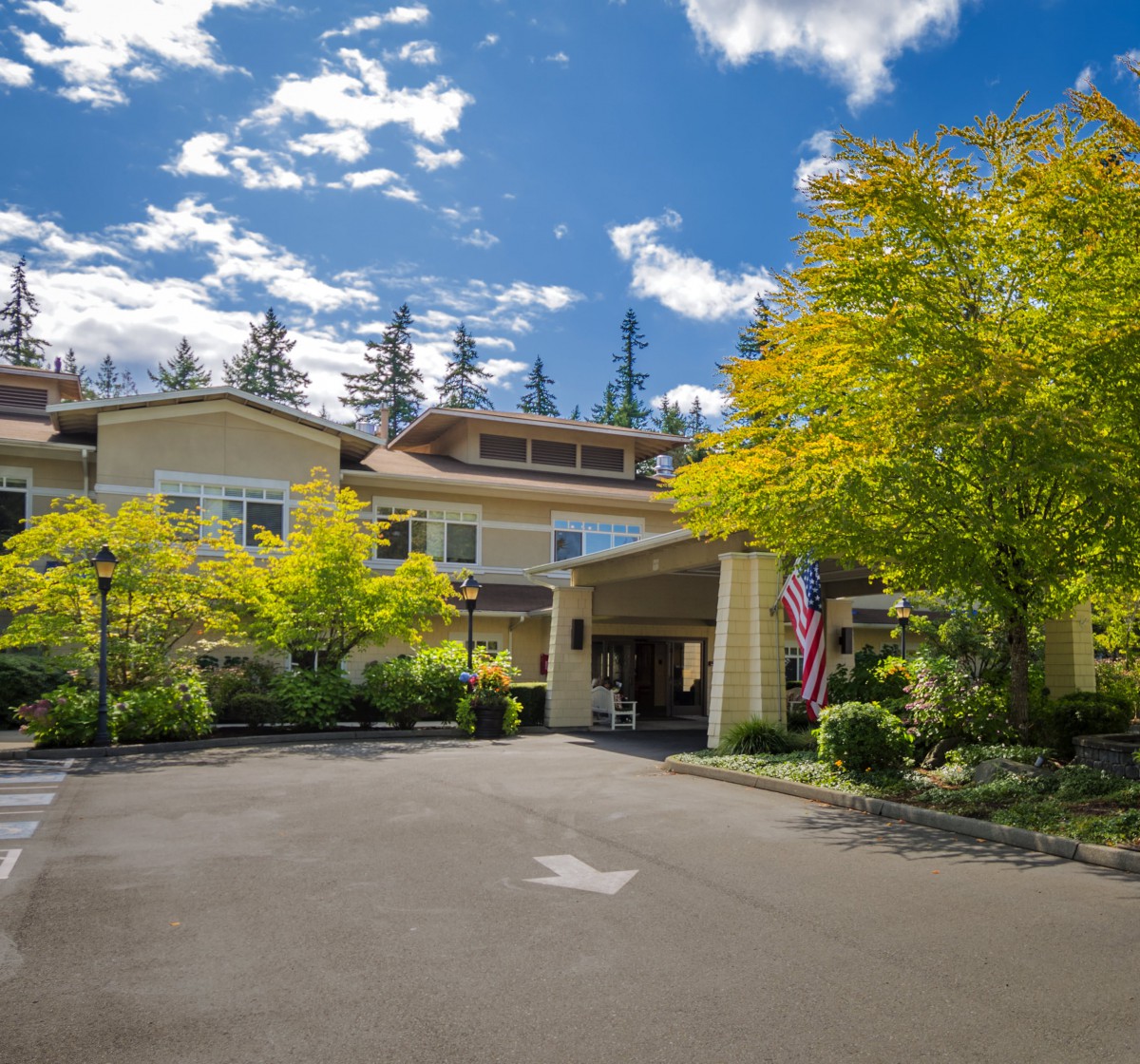 A welcoming entrance to a building surrounded by lush greenery under a partly cloudy sky.