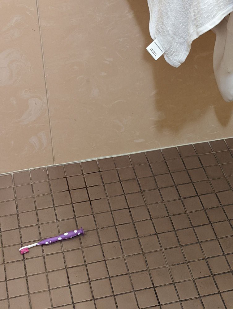 A toothbrush lying on a tiled bathroom floor.