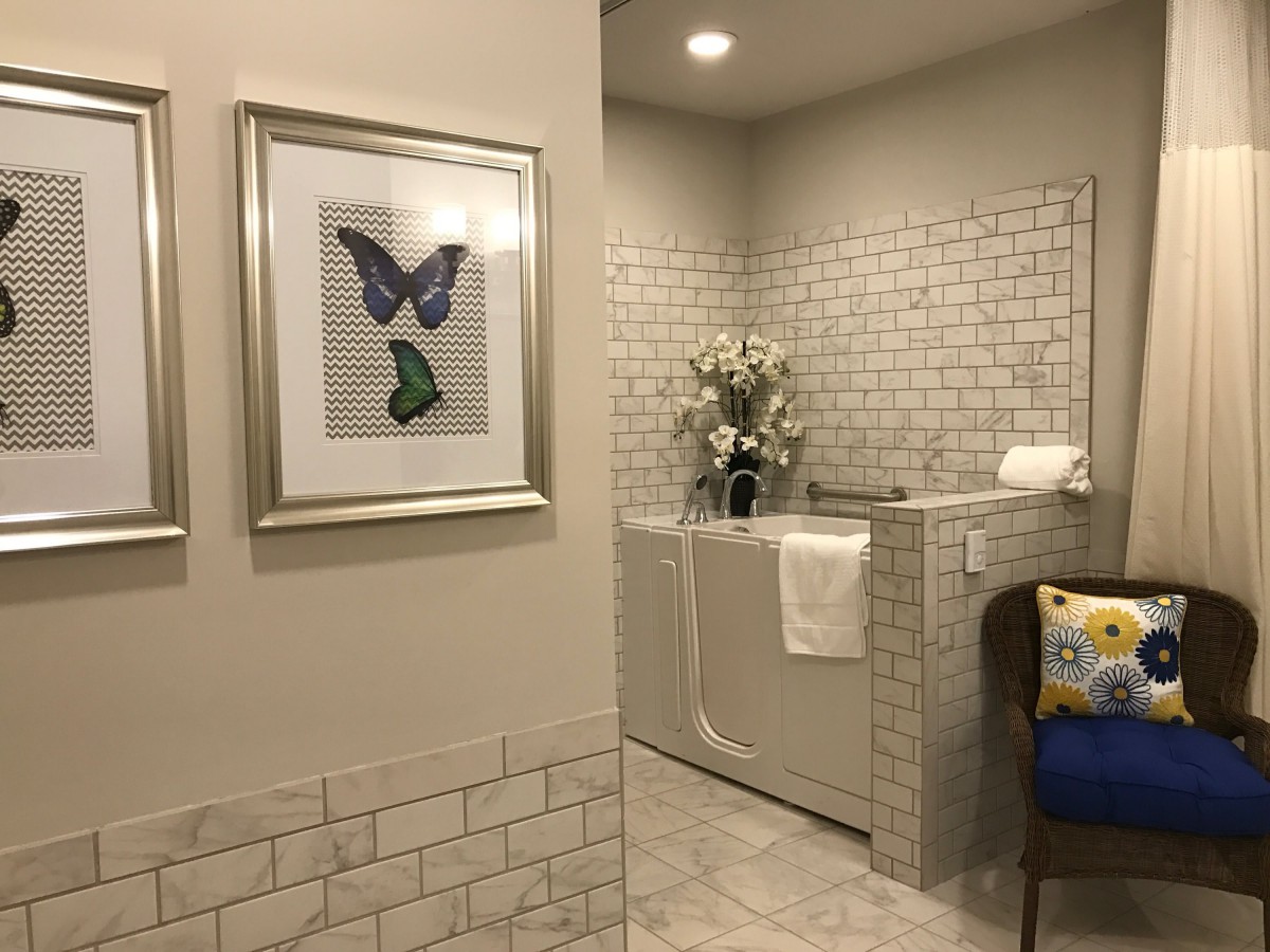 A modern bathroom with a bathtub, tiled walls, and butterfly artwork.