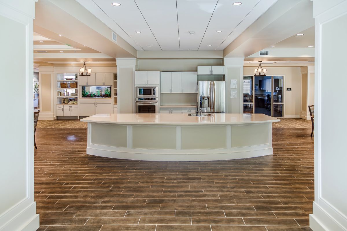 A modern kitchen with white cabinetry, a large island counter, and hardwood flooring.