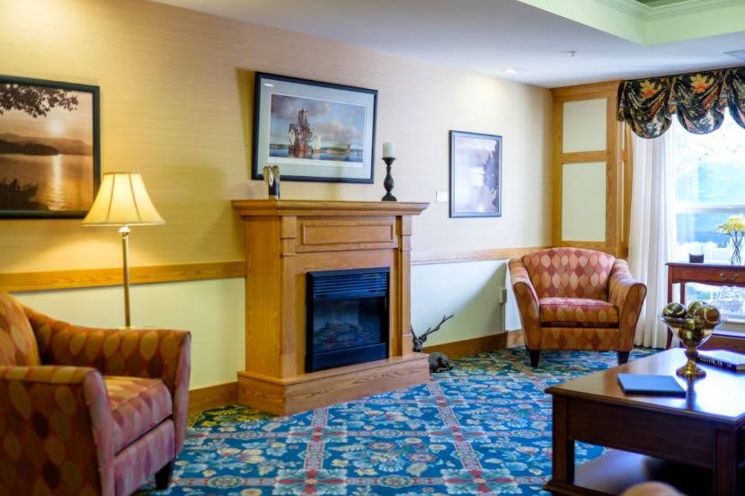 A cozy living room with a fireplace, armchairs, and decorative artwork.
