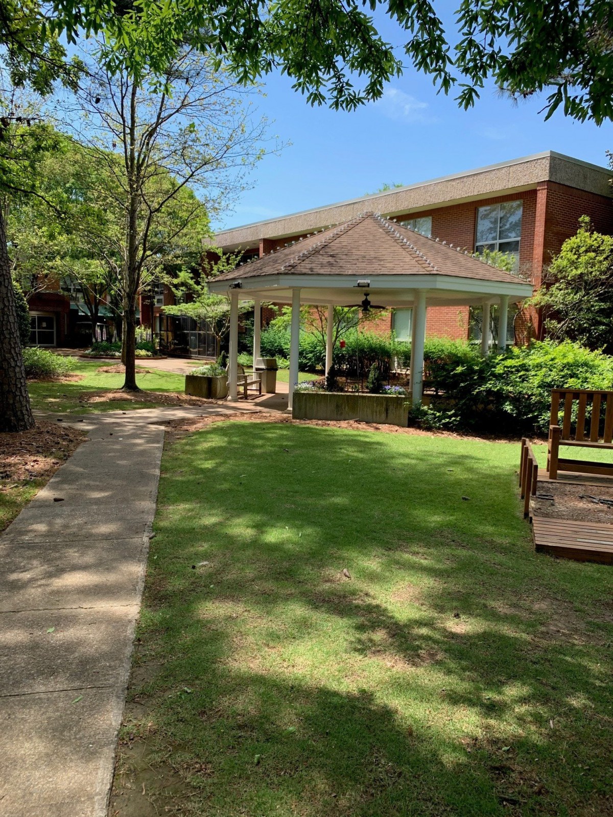 A peaceful garden with a gazebo and surrounding greenery on a sunny day.