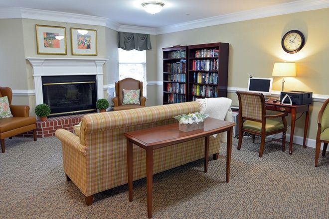Cozy living room with a sofa, armchair, fireplace, bookshelf, and computer desk.