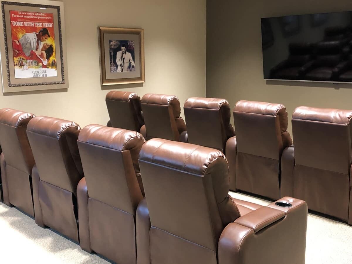 A cozy home theater with leather recliners and a large screen.