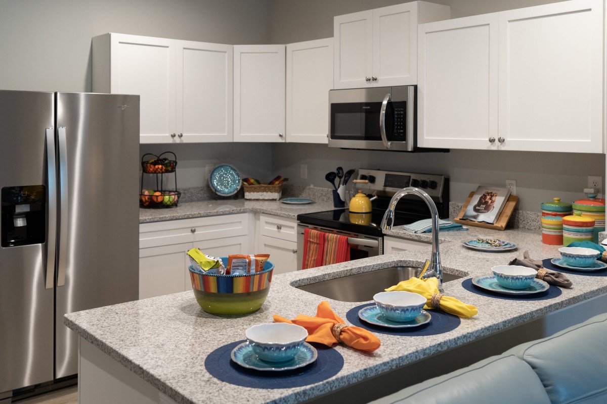 A modern kitchen with white cabinets and a neatly arranged dining setup on the countertop.