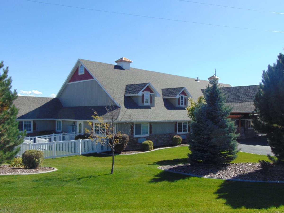 A suburban house with a well-maintained lawn and trees under a clear blue sky.