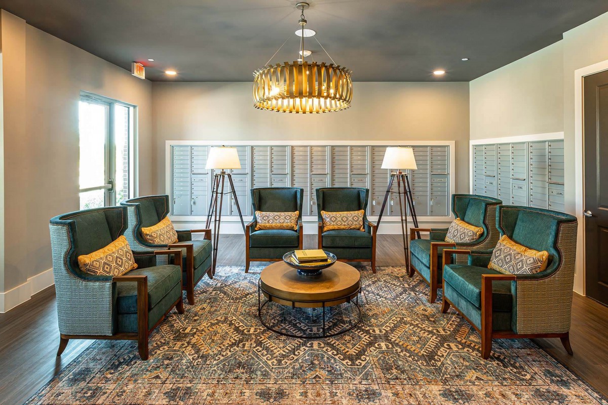 A stylish living room with green armchairs, a central coffee table, and elegant lighting.