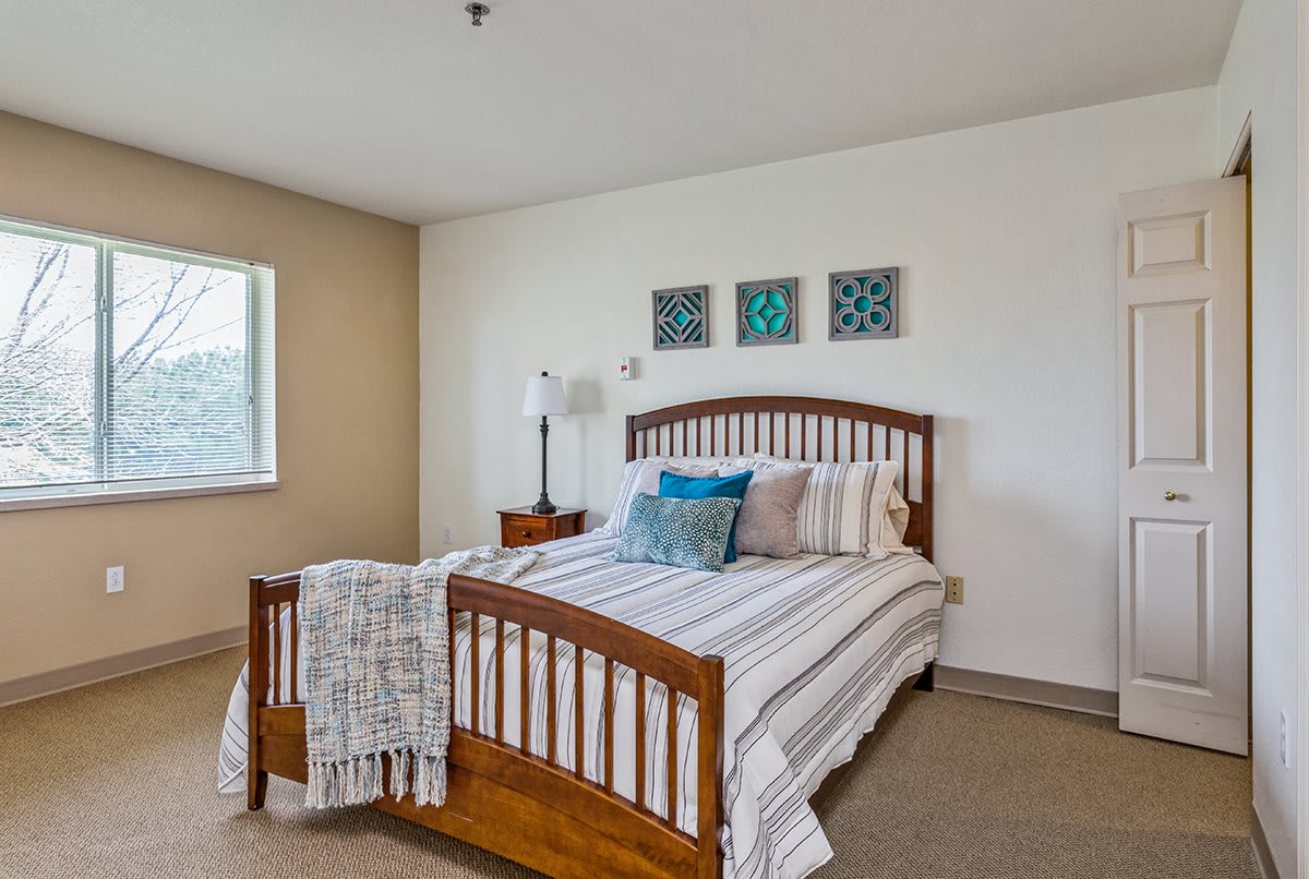 A cozy bedroom featuring a wooden bed with striped bedding, decorative pillows, and wall art.
